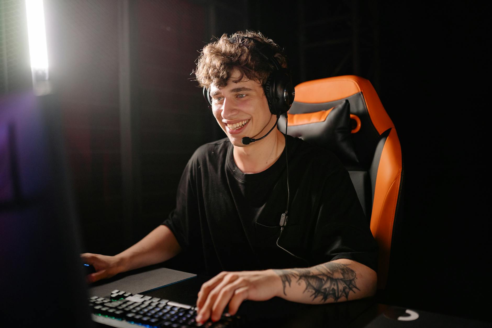 photo of a man in a black shirt smiling while playing on a computer